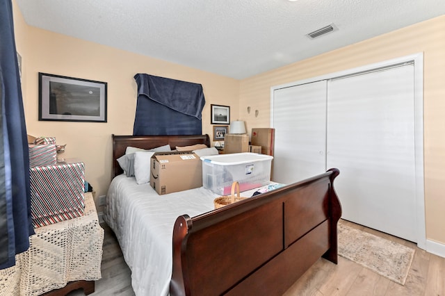 bedroom featuring a closet, a textured ceiling, and light hardwood / wood-style flooring