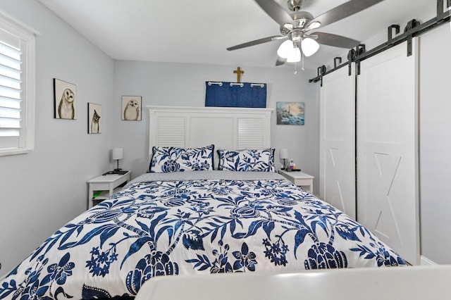 bedroom featuring a barn door and ceiling fan