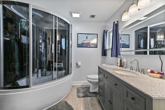 full bathroom featuring wood-type flooring, combined bath / shower with glass door, toilet, and vanity