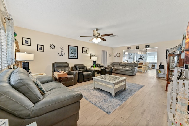 living room with light wood-type flooring, a textured ceiling, and ceiling fan