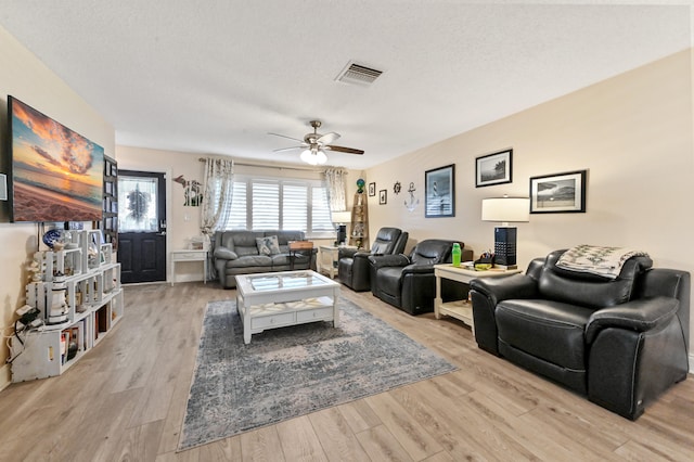 living room featuring a textured ceiling, light wood-type flooring, and ceiling fan