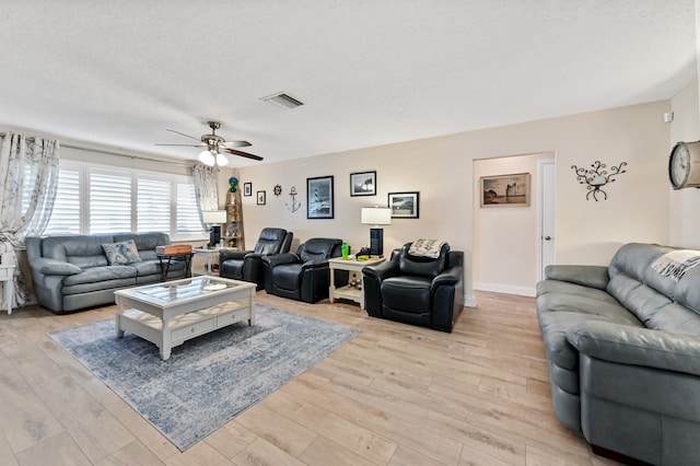 living room featuring ceiling fan, a textured ceiling, and light wood-type flooring