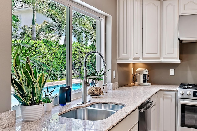 kitchen featuring white cabinetry, sink, light stone countertops, extractor fan, and appliances with stainless steel finishes