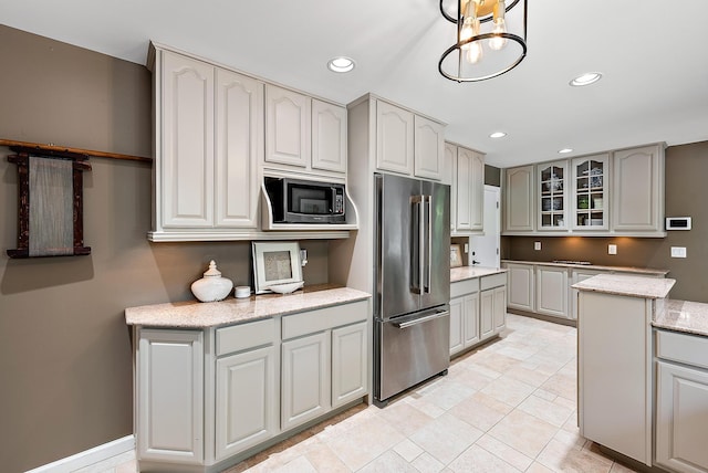 kitchen featuring appliances with stainless steel finishes, light tile patterned floors, gray cabinets, and light stone counters