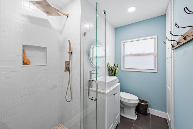 bathroom featuring tile patterned flooring, vanity, toilet, and a shower with door