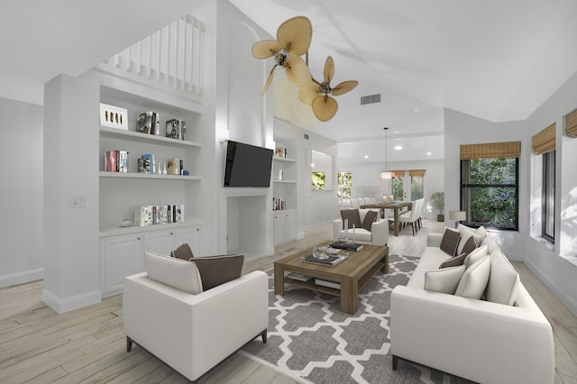 living room featuring vaulted ceiling, ceiling fan, light hardwood / wood-style flooring, and built in shelves