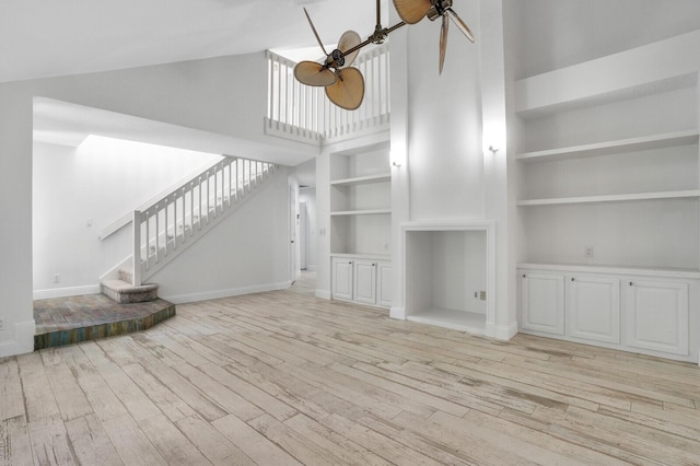 unfurnished living room featuring ceiling fan, light hardwood / wood-style flooring, built in features, and high vaulted ceiling