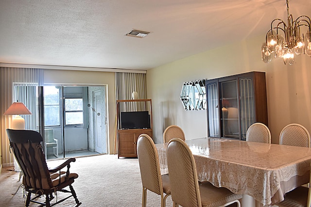 dining area featuring a textured ceiling, light colored carpet, and a chandelier