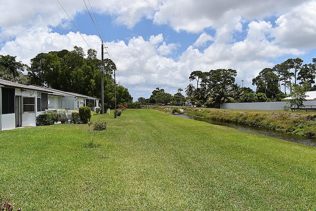 view of yard featuring a sunroom and a water view