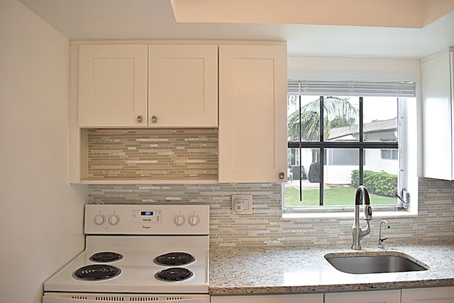 kitchen with white cabinets, sink, white stove, and light stone counters