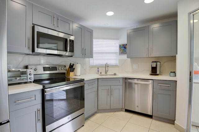 kitchen featuring light tile patterned floors, gray cabinetry, sink, and appliances with stainless steel finishes