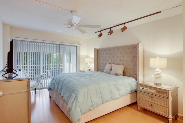 bedroom featuring access to outside, a textured ceiling, rail lighting, ceiling fan, and light hardwood / wood-style flooring