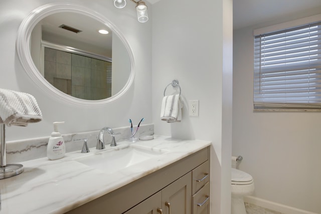 bathroom with toilet, vanity, and a shower with shower door