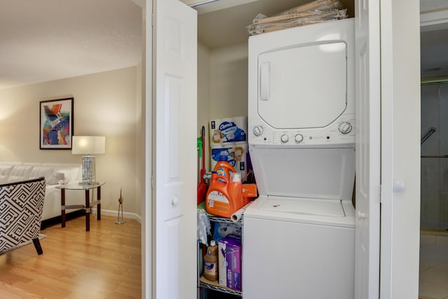 clothes washing area featuring light wood-type flooring and stacked washer / dryer