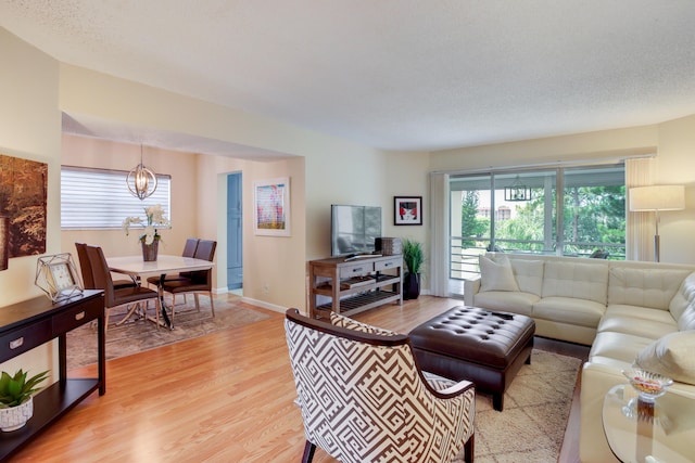 living room featuring a chandelier, a textured ceiling, and light hardwood / wood-style flooring