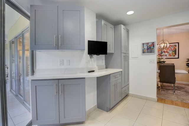 kitchen with gray cabinets, pendant lighting, an inviting chandelier, and light hardwood / wood-style floors