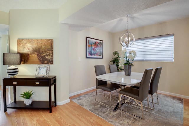 dining space featuring a chandelier, a textured ceiling, and light hardwood / wood-style flooring