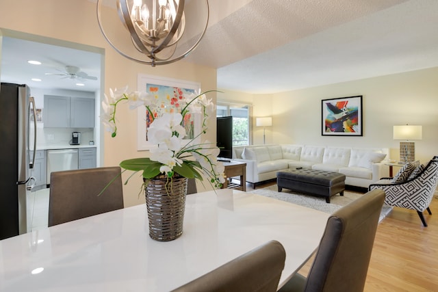 dining area featuring a textured ceiling, light wood-type flooring, and ceiling fan