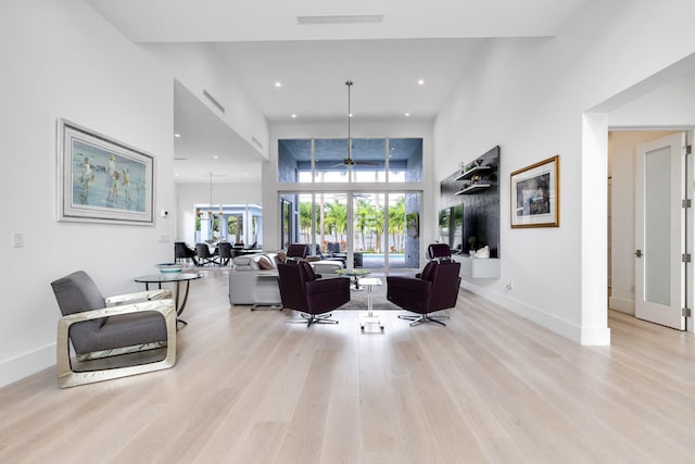 living room featuring a towering ceiling, light hardwood / wood-style flooring, and a chandelier