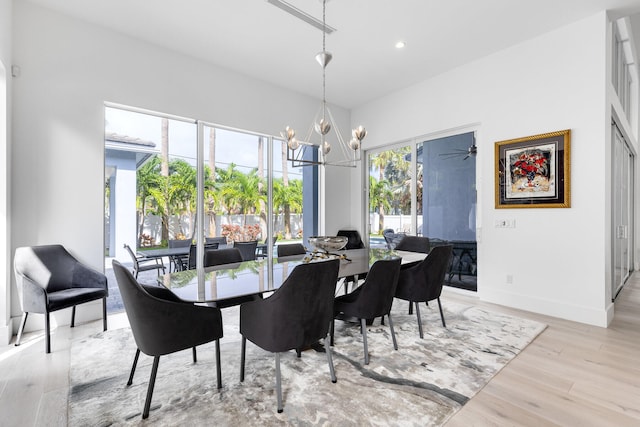 dining area with light hardwood / wood-style floors and ceiling fan with notable chandelier