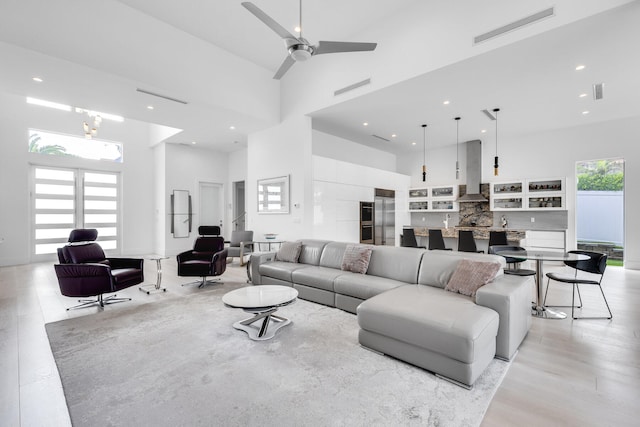 living room with light hardwood / wood-style floors, ceiling fan, and a high ceiling