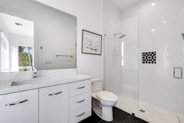 bathroom featuring vanity, a shower with shower door, tile patterned flooring, and toilet