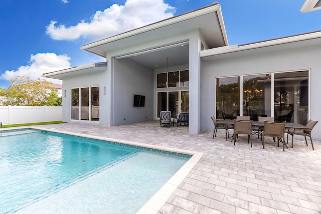 rear view of property featuring a fenced in pool and a patio