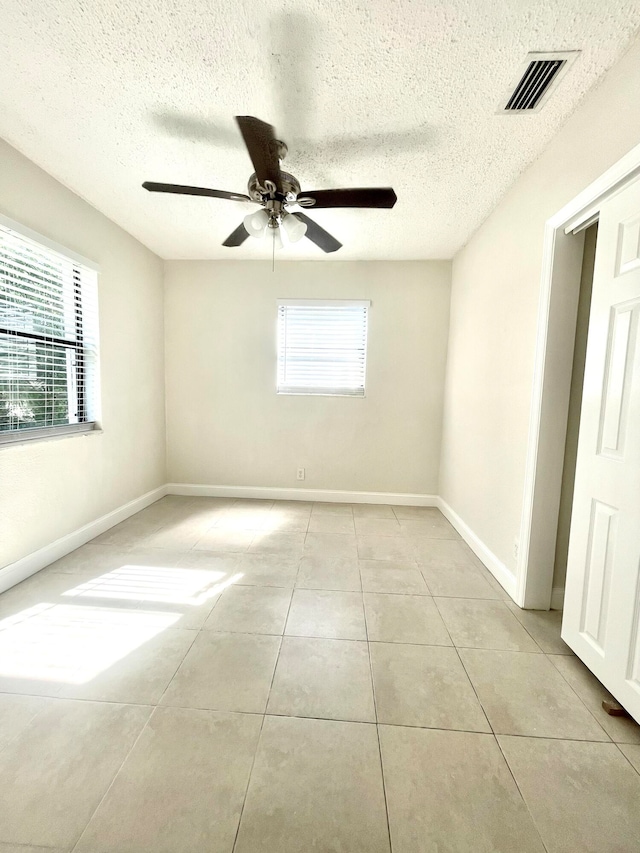 tiled spare room with ceiling fan and a textured ceiling