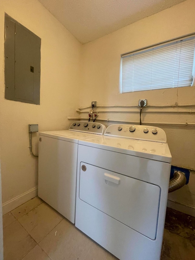 laundry room with washing machine and clothes dryer, electric panel, and light tile patterned flooring