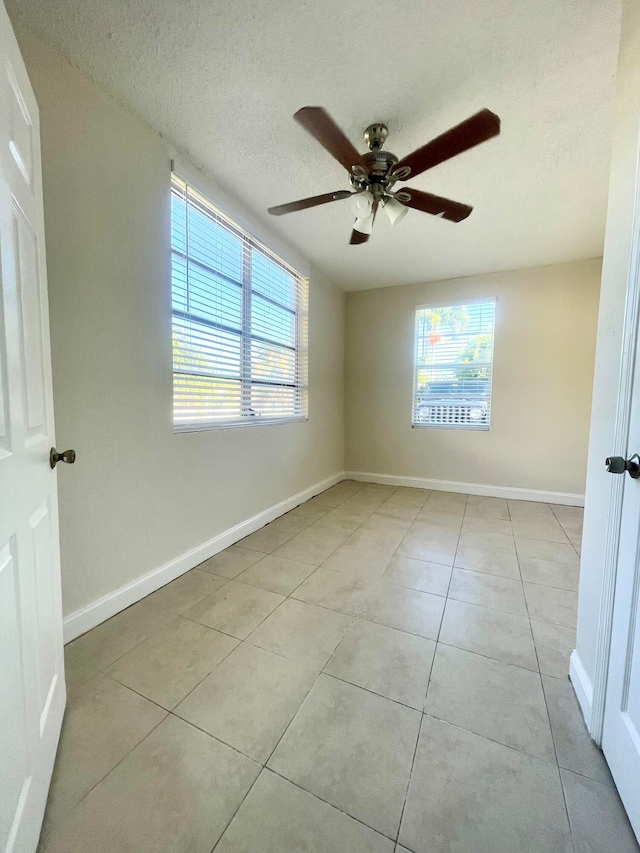 unfurnished room with ceiling fan, light tile patterned floors, and a textured ceiling