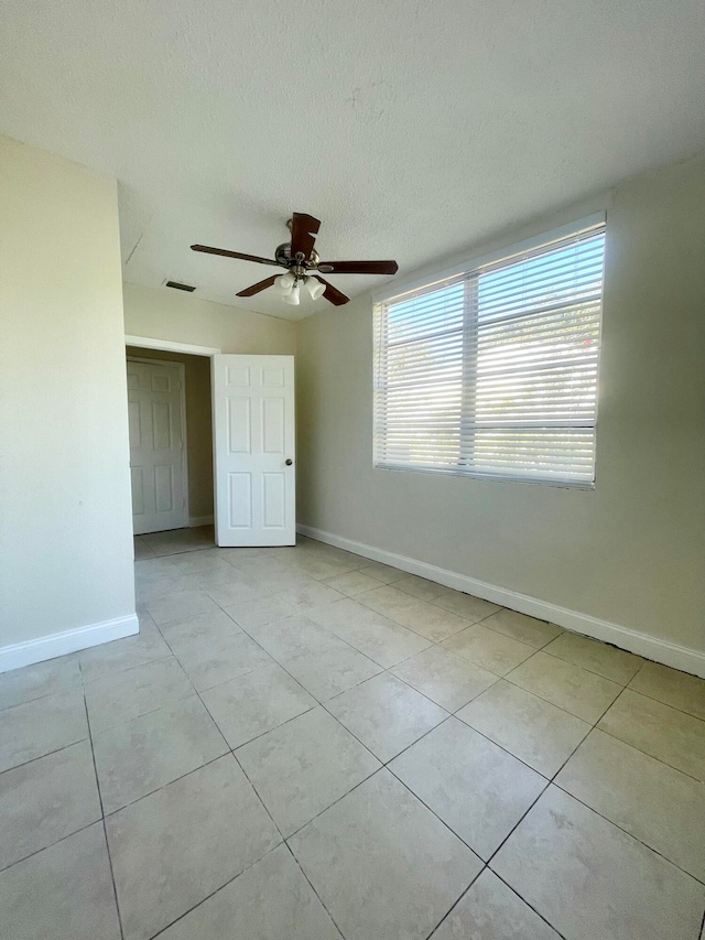 spare room with ceiling fan, light tile patterned floors, and a textured ceiling