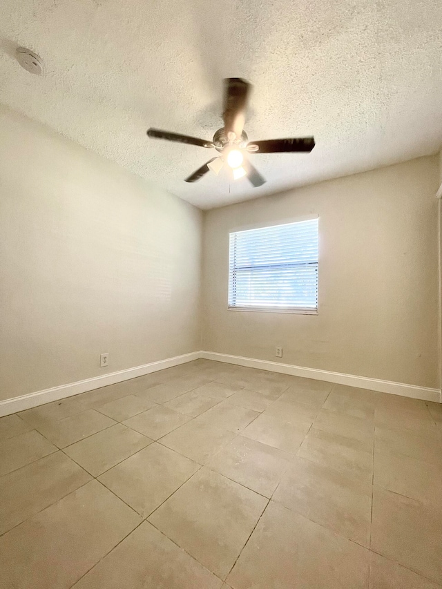 unfurnished room with ceiling fan, light tile patterned floors, and a textured ceiling