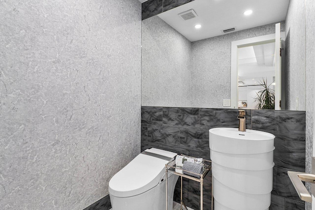 bathroom featuring toilet and tile walls