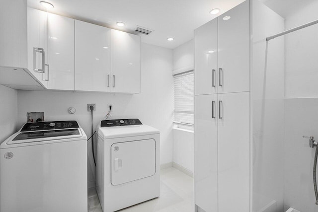 laundry area with washing machine and dryer, cabinets, and light tile patterned flooring