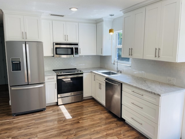 kitchen featuring appliances with stainless steel finishes, dark hardwood / wood-style floors, pendant lighting, sink, and white cabinets