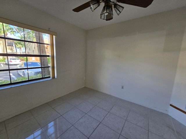 empty room with ceiling fan, plenty of natural light, and light tile patterned floors