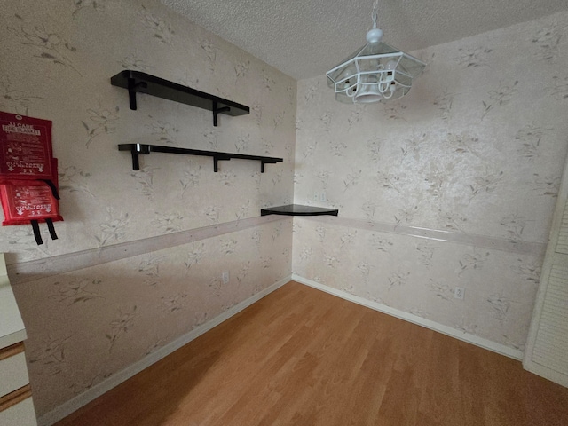 unfurnished dining area with an inviting chandelier, wood-type flooring, and a textured ceiling