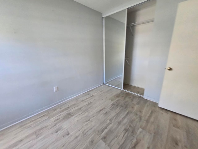 unfurnished bedroom with a closet and light wood-type flooring