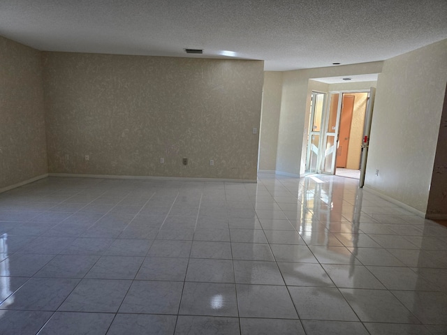 empty room with a textured ceiling and light tile patterned floors