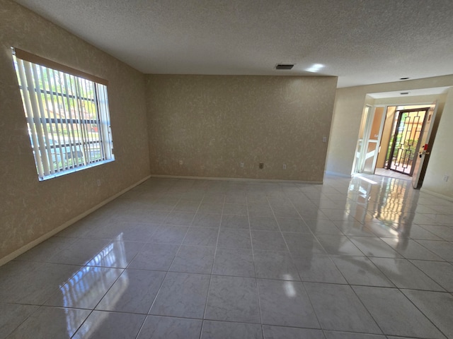 empty room featuring a textured ceiling and light tile patterned floors