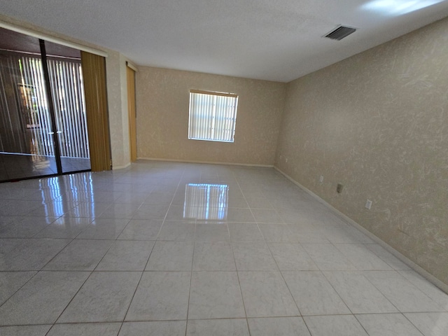 unfurnished room with a textured ceiling and light tile patterned floors