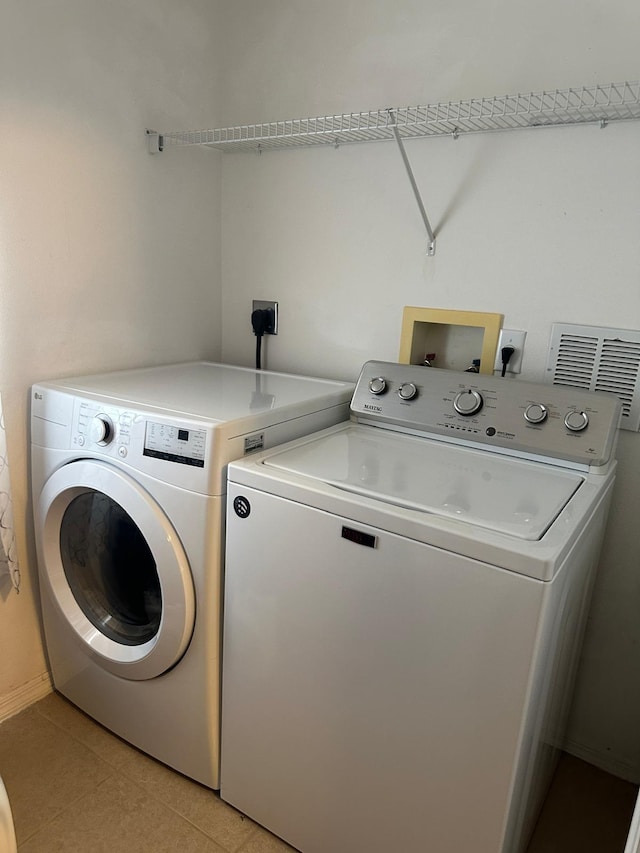 clothes washing area featuring washing machine and clothes dryer and light tile patterned floors