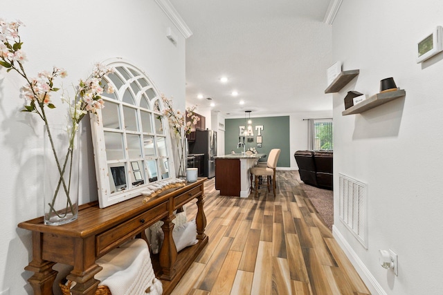 interior space featuring sink, ornamental molding, and light wood-type flooring