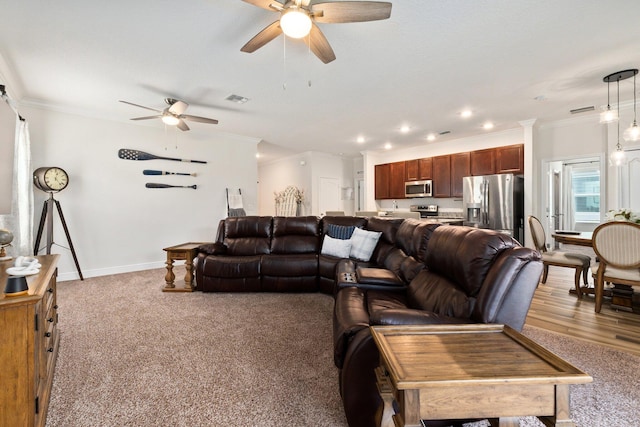 living room with crown molding, ceiling fan, and light carpet