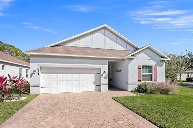 single story home featuring decorative driveway, roof with shingles, stucco siding, an attached garage, and a front lawn