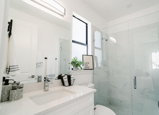 bathroom featuring toilet, vanity, and a shower with door