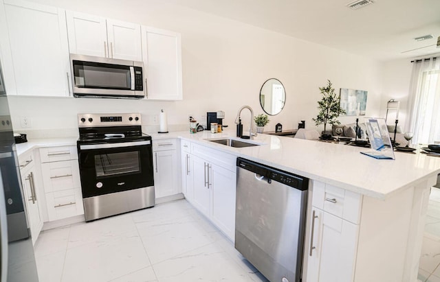 kitchen with white cabinets, kitchen peninsula, stainless steel appliances, and sink