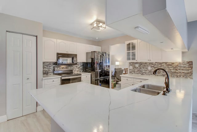 kitchen featuring white cabinetry, sink, stainless steel appliances, kitchen peninsula, and decorative backsplash