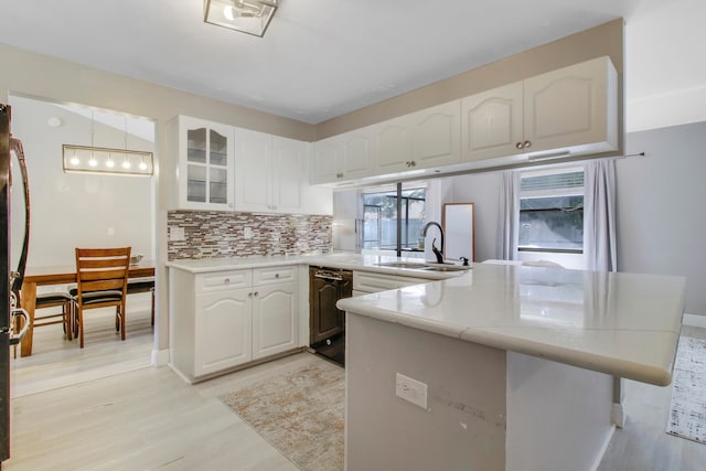 kitchen with white cabinets, kitchen peninsula, sink, and tasteful backsplash