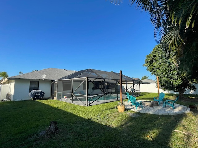 rear view of house with a fire pit, a lawn, a fenced in pool, a lanai, and a patio